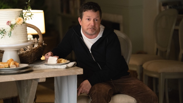 alt="Michael J Fox as Gerry sitting in a chair eating food in Shrinking.jpg"