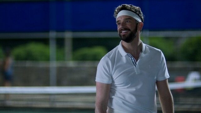 alt="Michael Urie as Brian playing tennis with a white sweatband on in Shrinking"