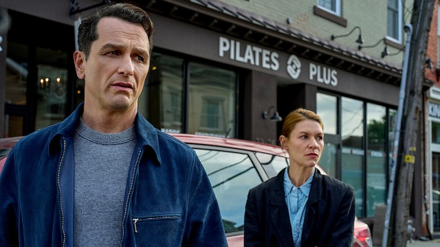 Claire Danes walking behind Matthew Rhys in front of a pilates studio
