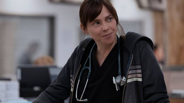 alt="Dr. Cassie McKay smiles slightly in the hospital dressed in scrubs"