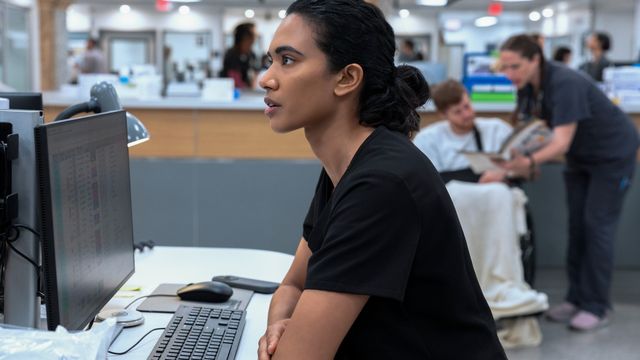 alt="Dr. Samira Mohan sits at a computer station in a hospital, focused on the screen."